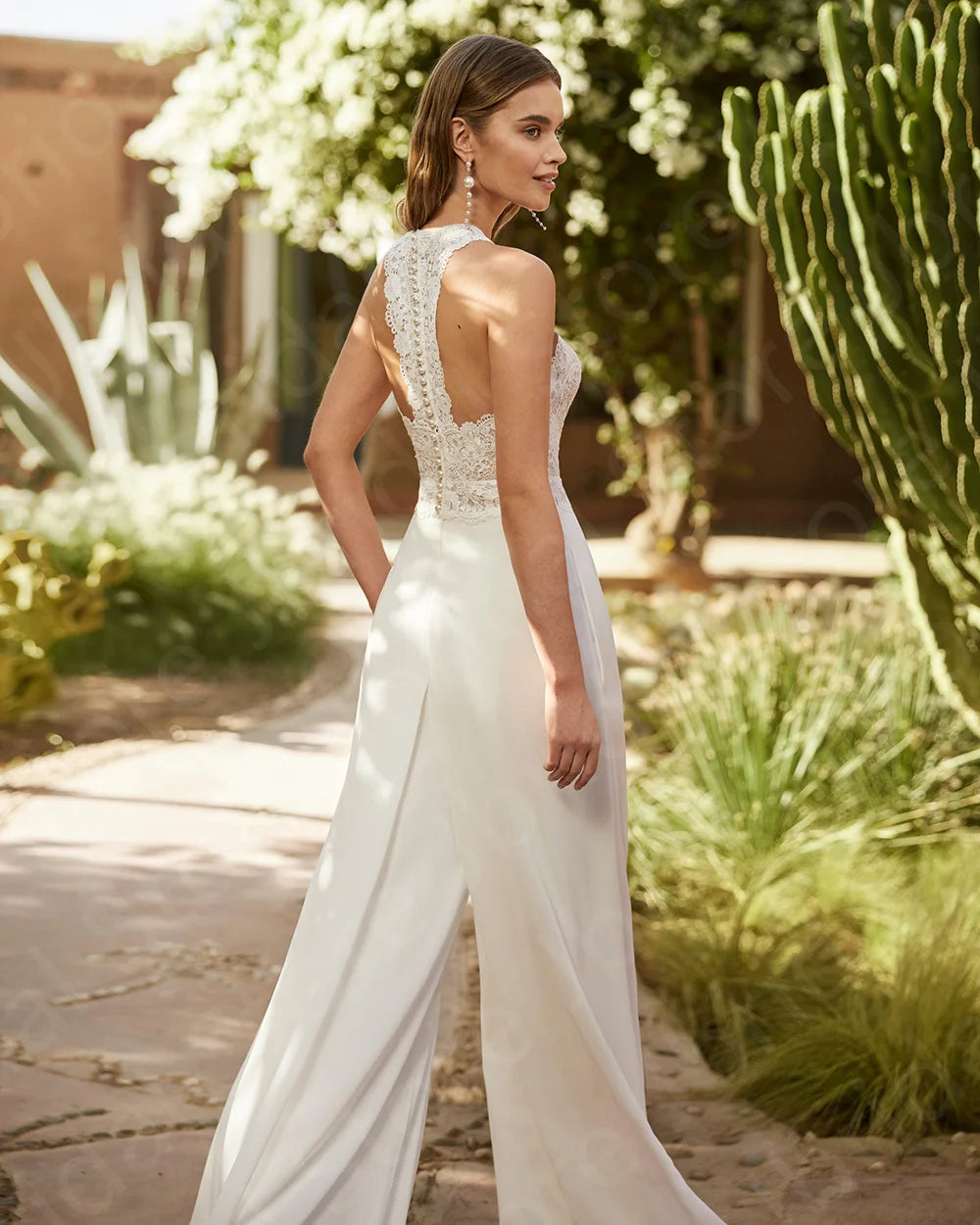 Woman wearing a bridal white lace halter top and wide-leg pants on a white background wedding jumpsuit