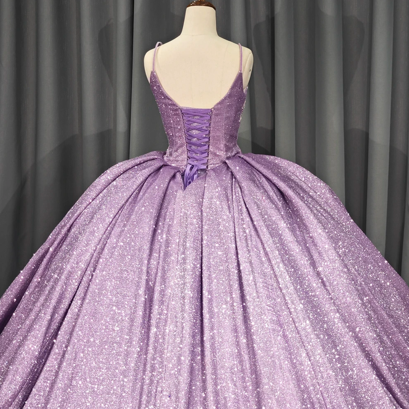 Back view of a stunning purple shiny quinceanera dress with a voluminous skirt and intricate lace details.