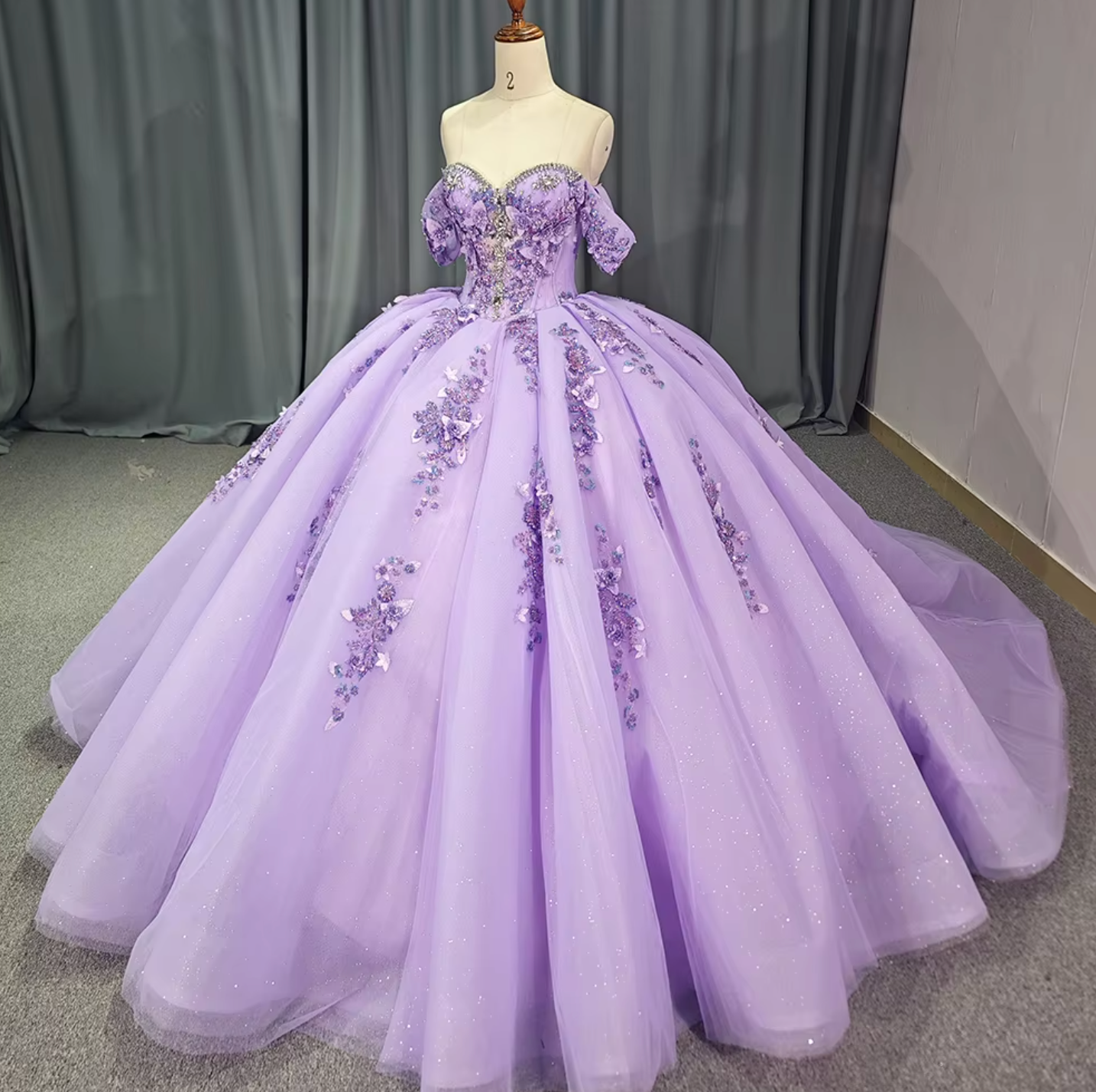 Purple Quinceanera dress with off-the-shoulder design, floral accents, and a full pleated skirt.