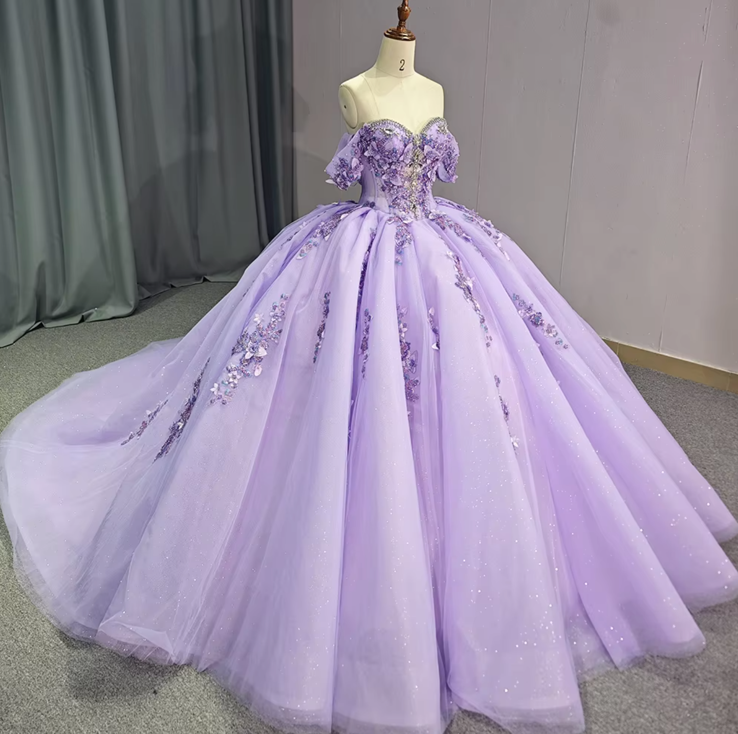 Purple Quinceanera dress with off-the-shoulder design, floral accents, and full tulle skirt.