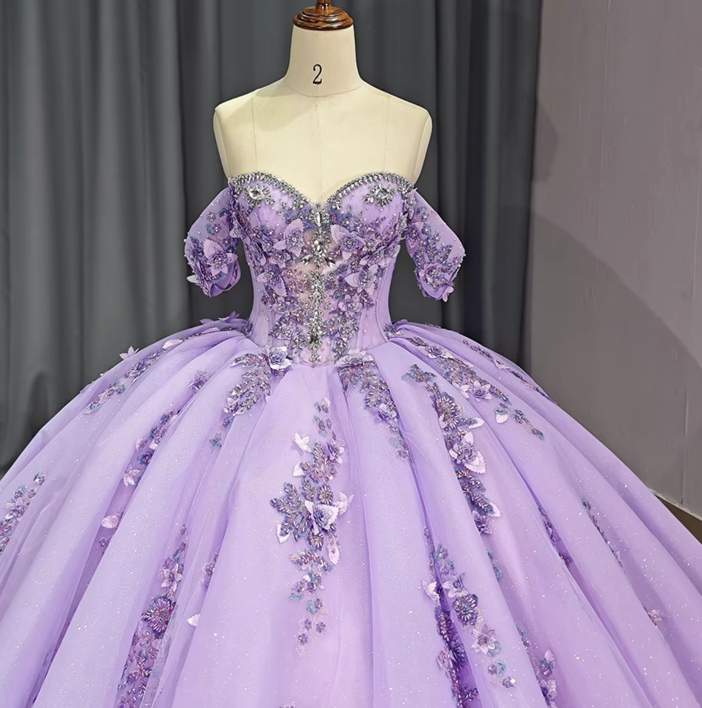 Off-the-shoulder purple Quinceanera dress with crystal accents and floral embellishments, perfect for a princess. Ball gown style.