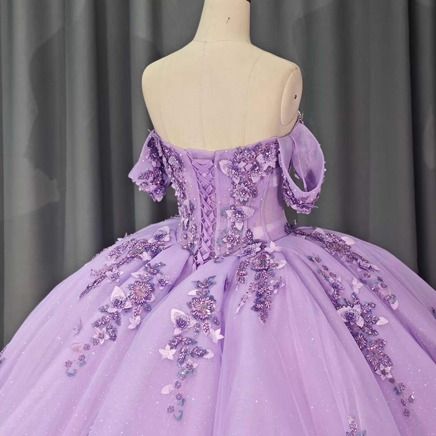 Back view of a purple quinceanera dress with off-the-shoulder sleeves and floral beadwork, showcasing a satin lace-up back.