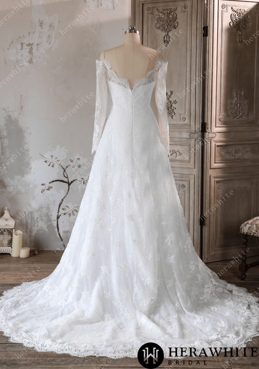 White lace wedding dress on a mannequin against a decorative wall.