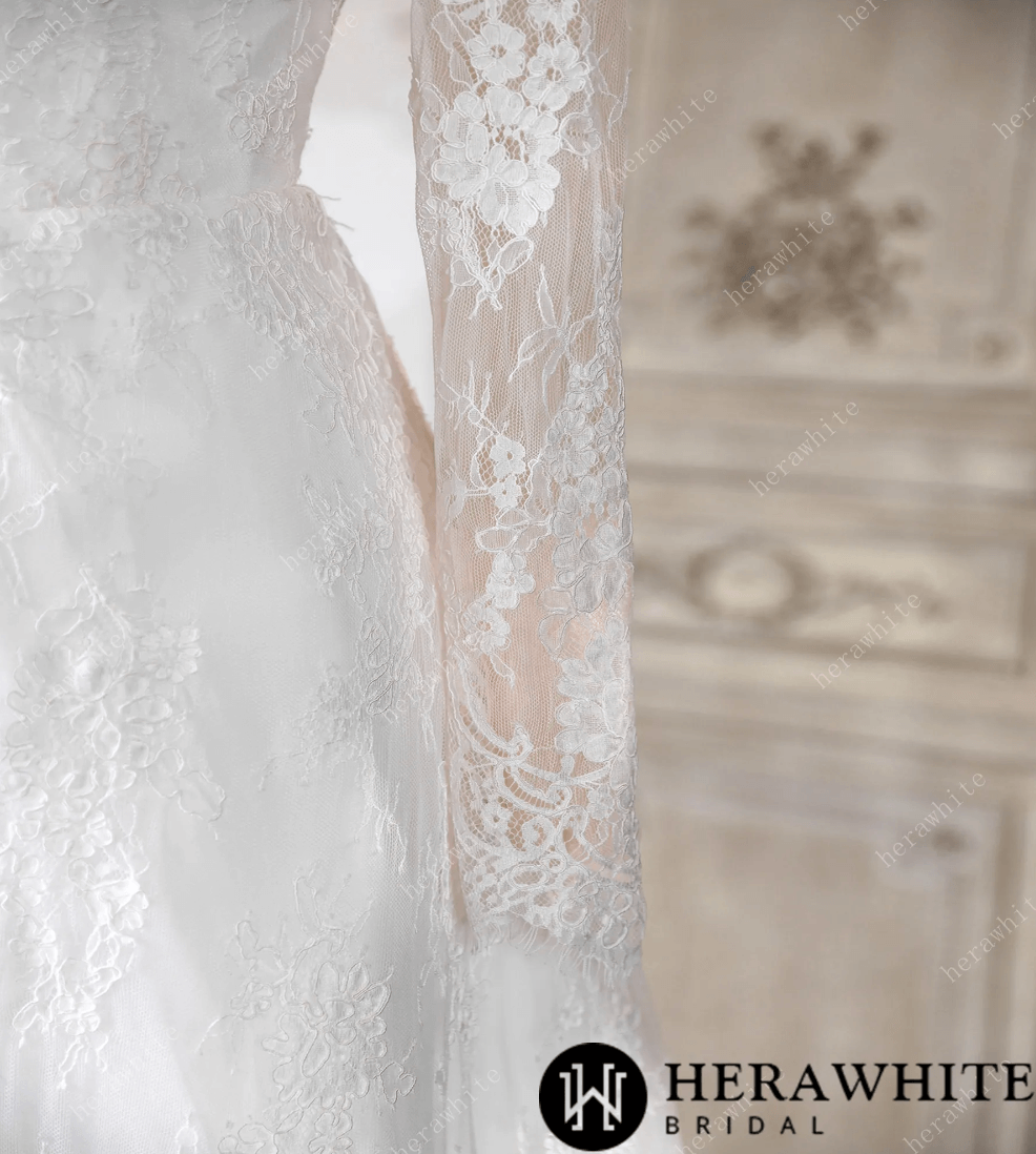White lace wedding dress on a mannequin against a decorative wall.