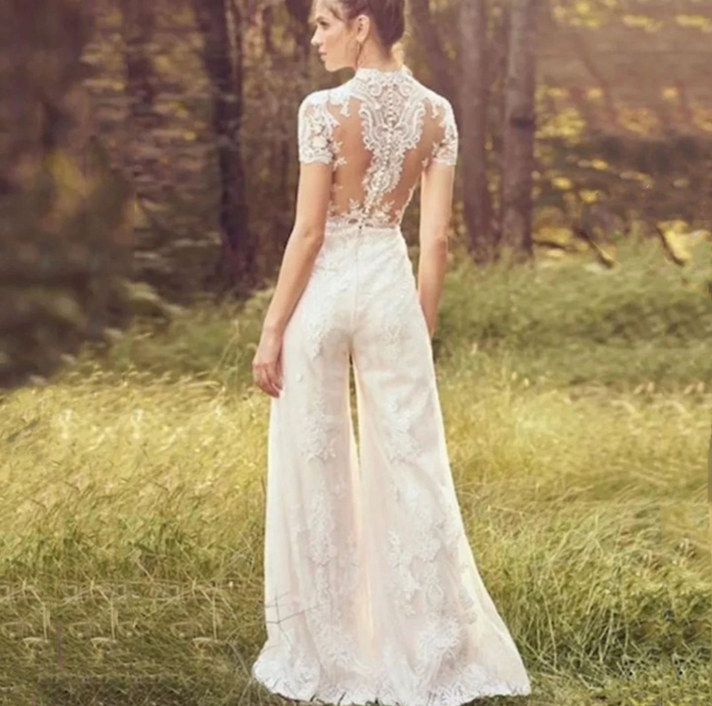 Back view of a woman in a satin and lace wedding day pants suit in a natural setting.