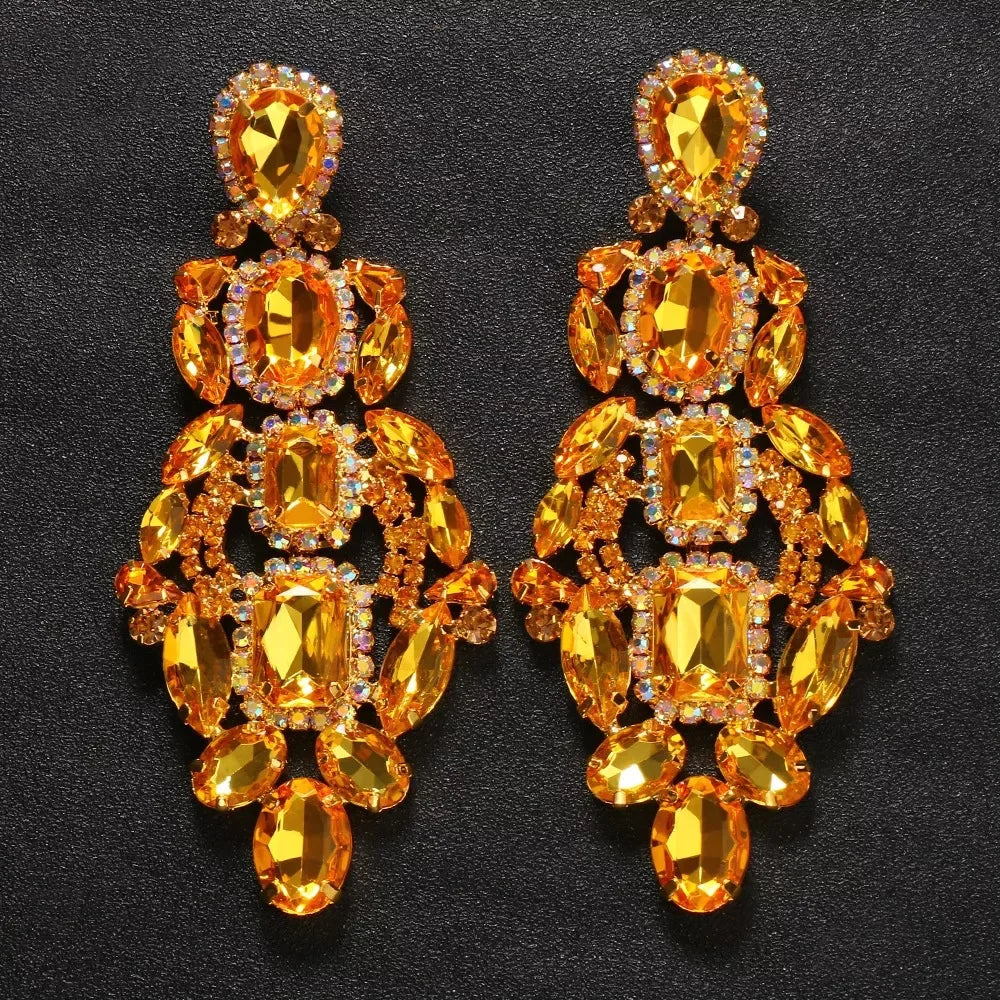 
                      
                        Pair of ornate earrings with orange gemstones on a black background
                      
                    