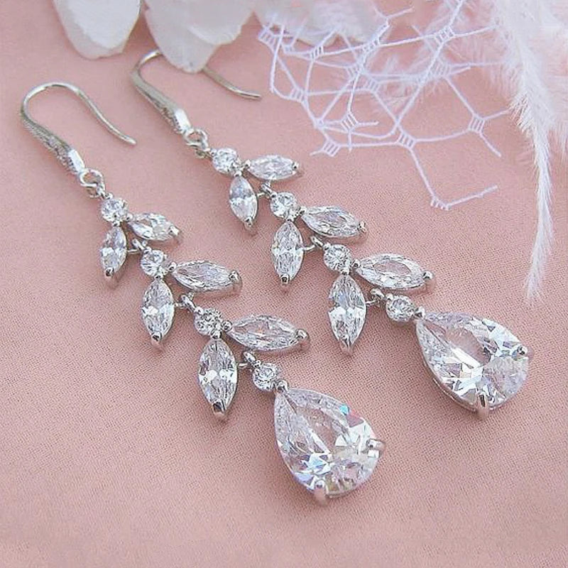 
                      
                        Silver earrings with clear gemstones on a pink background
                      
                    