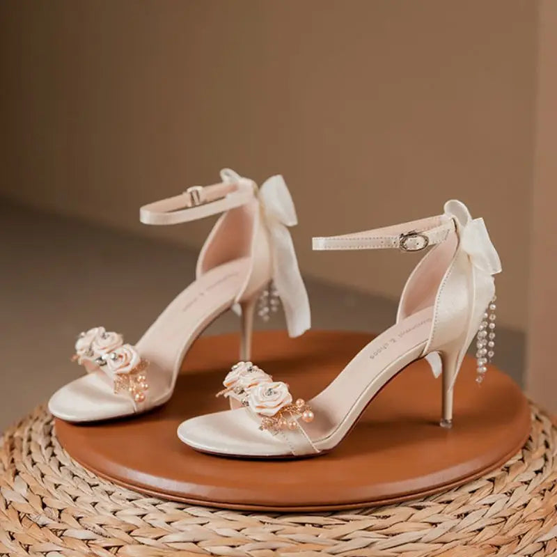 wedding bridal shoes open toe with floral accents on the toe bridge with a ankle strap and heel bow with pearl beading and heels.