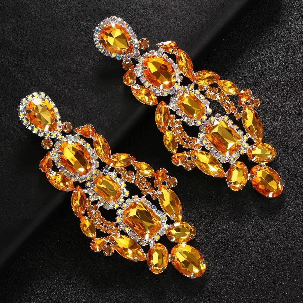
                      
                        Pair of ornate earrings with orange gemstones on a black background
                      
                    