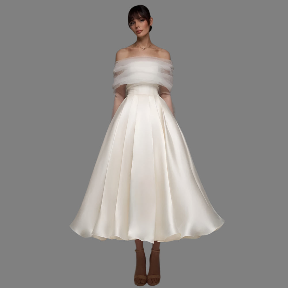 Woman wearing a white off-shoulder dress with sheer overlay on a gray background