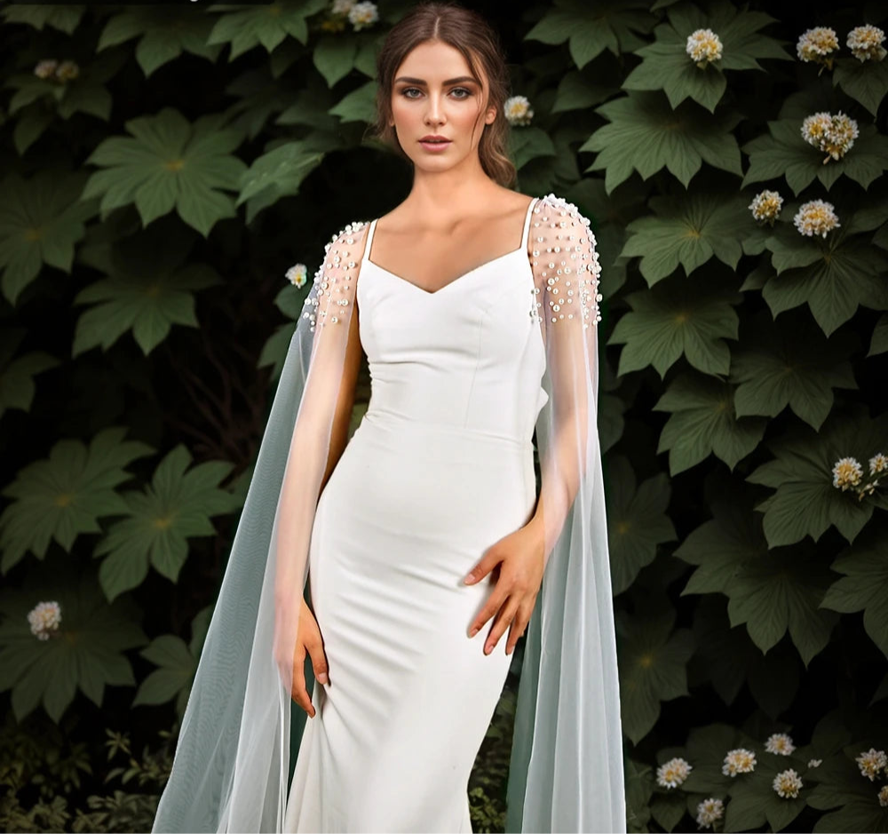 Woman in a white dress with a sheer overlay against a green leafy background