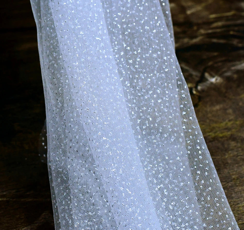 
                      
                        Close-up of a sheer fabric with small embellishments on a textured background
                      
                    