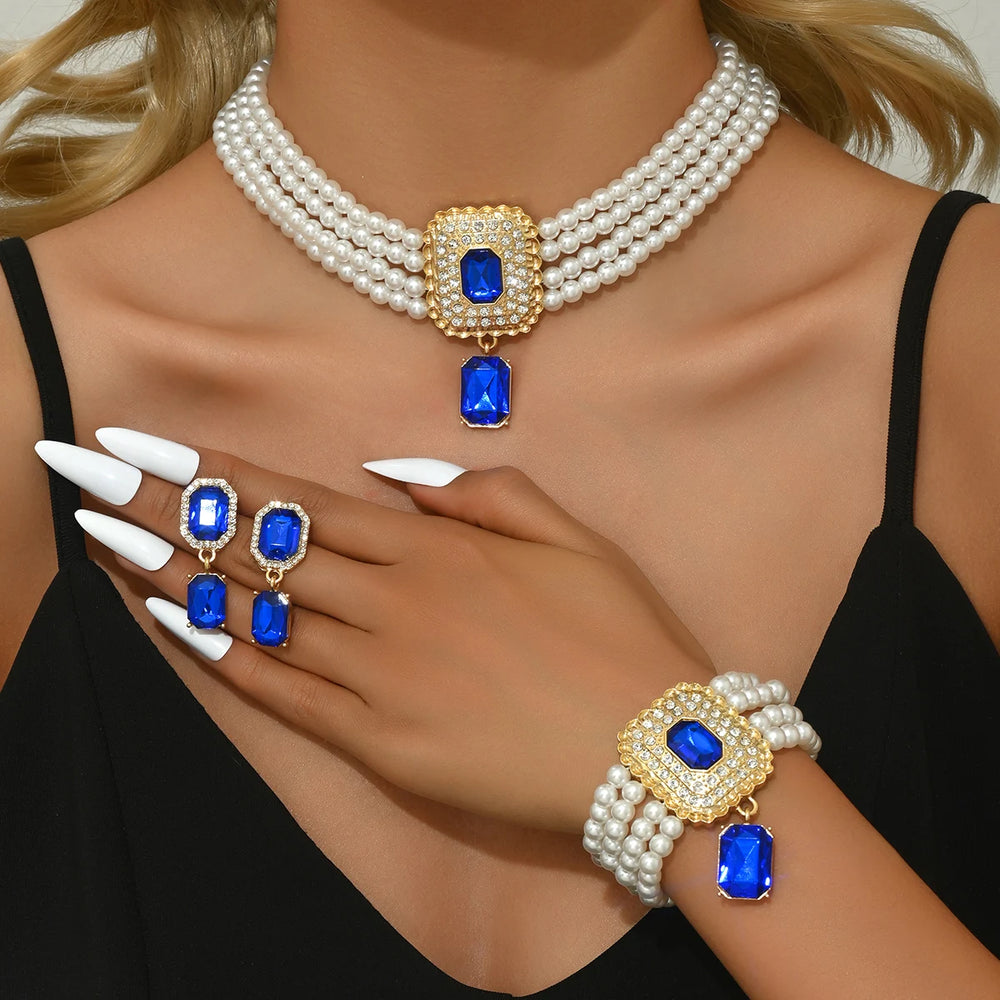 
                      
                        Jewelry set with pearls, blue gemstones, and gold accents on a model.
                      
                    