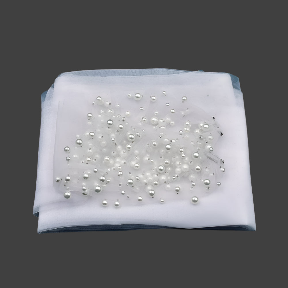 
                      
                        White fabric with pearl embellishments on a dark green background 
                      
                    