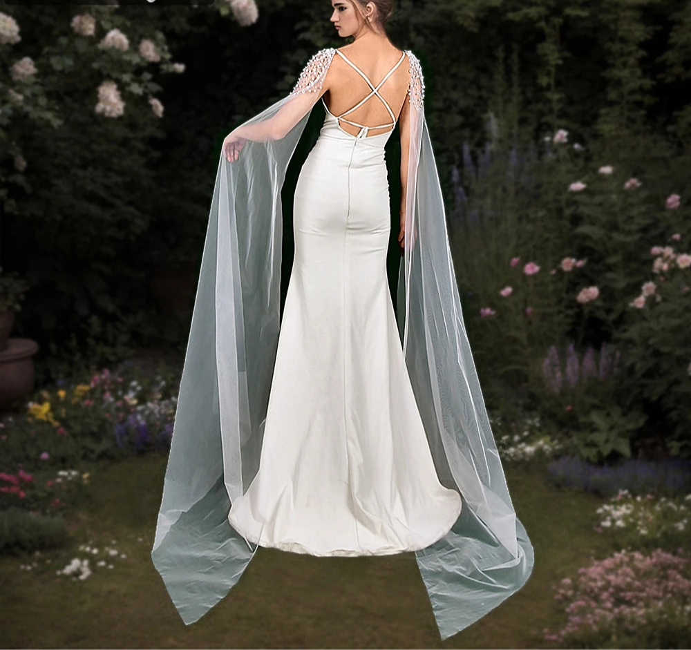 
                      
                        Woman in a white wedding dress with a long train standing in a garden setting.
                      
                    