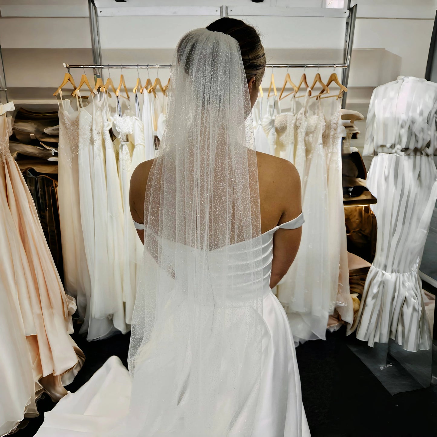 Person wearing a white wedding dress with a veil in a bridal shop.