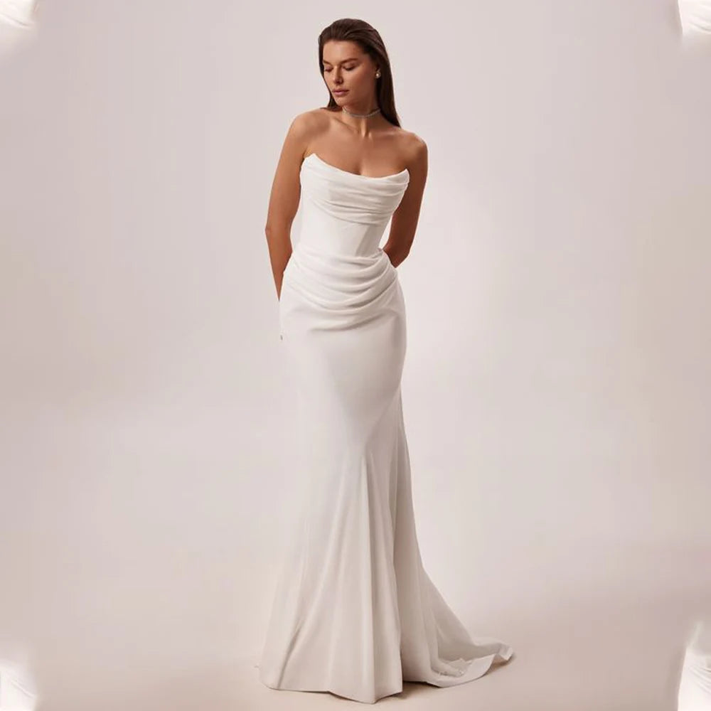 Woman wearing a strapless white wedding dress on a plain background