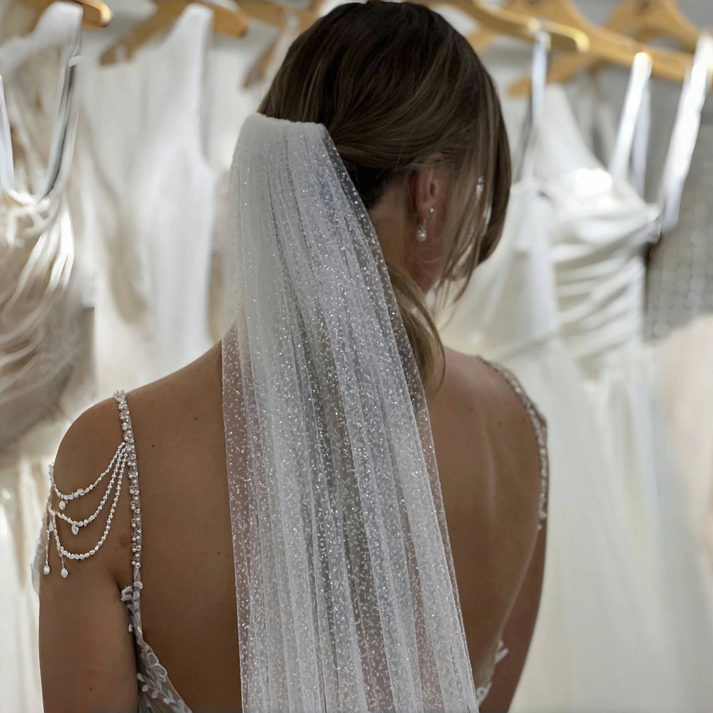 Woman wearing a wedding dress with a veil in a bridal shop.