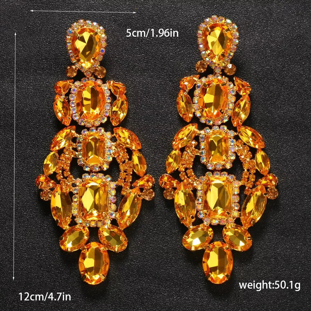 Pair of ornate earrings with yellow gemstones on a black background
