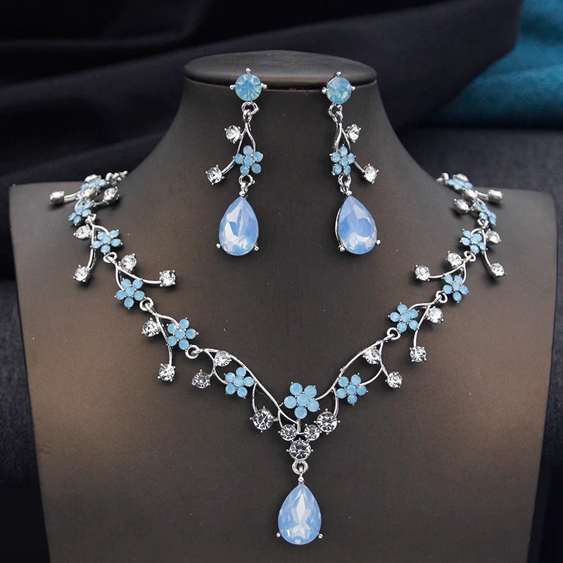 
                      
                        Crystal Rhinestone Bridal Jewelry Set featuring blue floral motifs and matching earrings, perfect for weddings.
                      
                    