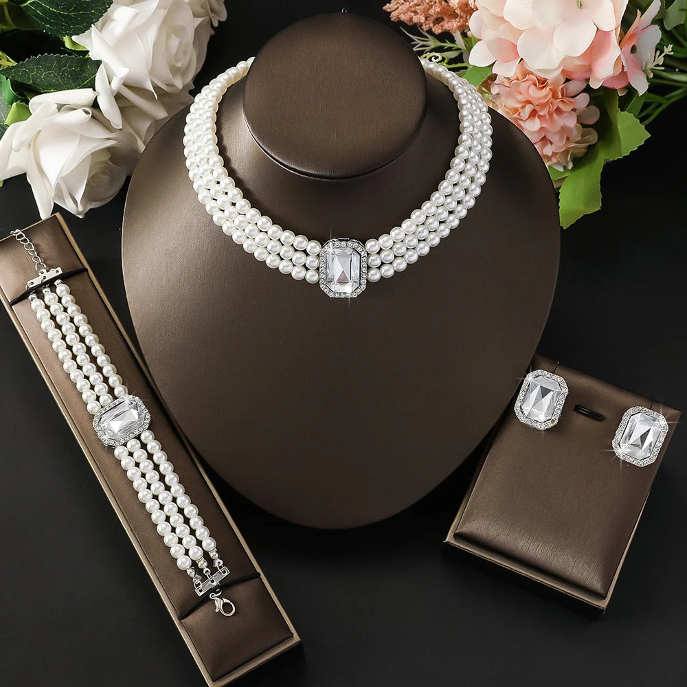 
                      
                        Pearl necklace with matching bracelet and earrings on a dark stand with flowers in the background
                      
                    
