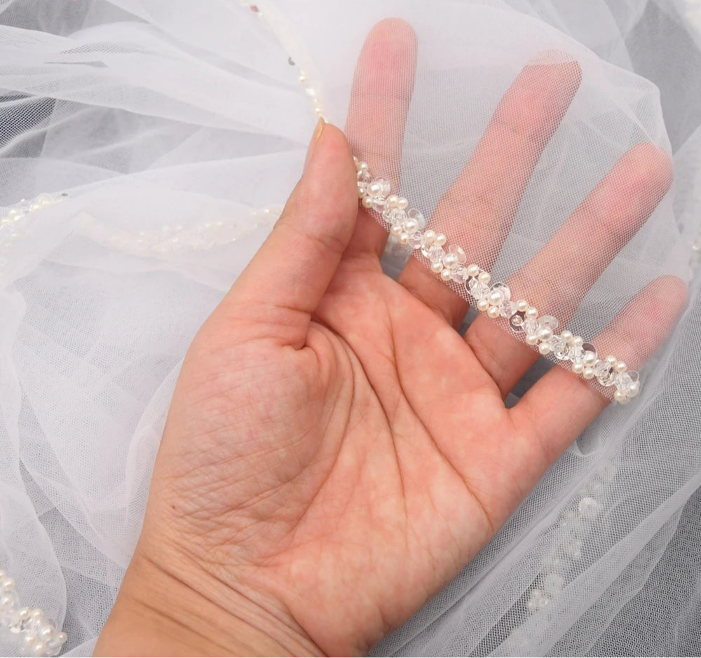 
                      
                        Hand holding a delicate crystal headband with a white fabric background
                      
                    