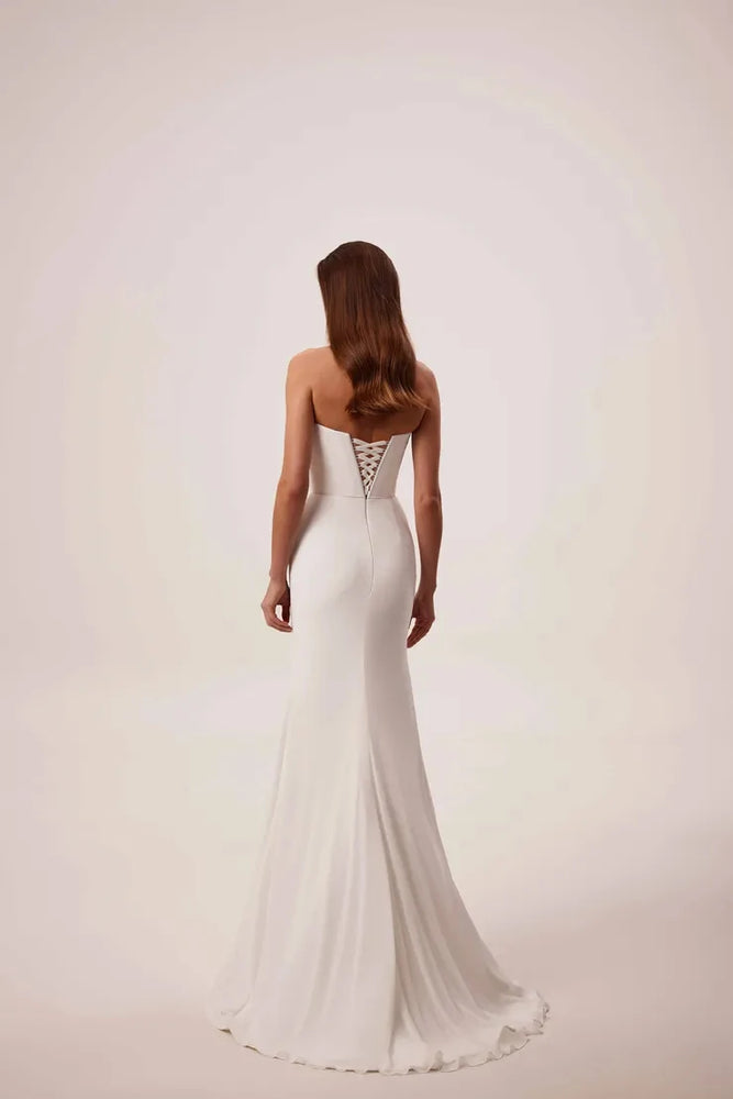 
                      
                        Woman wearing a strapless white wedding dress on a plain background
                      
                    