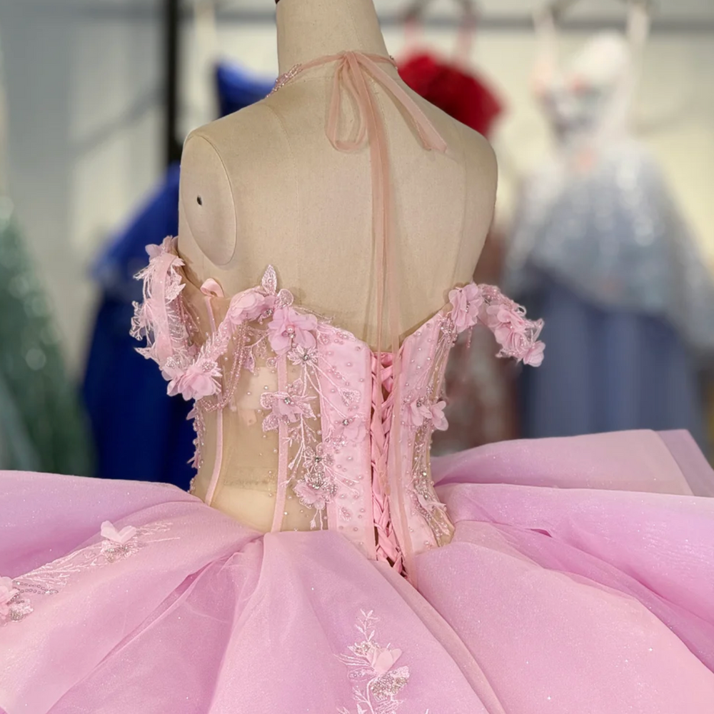 
                      
                        Pink evening gown with floral details on a mannequin in a room with other colorful dresses.
                      
                    