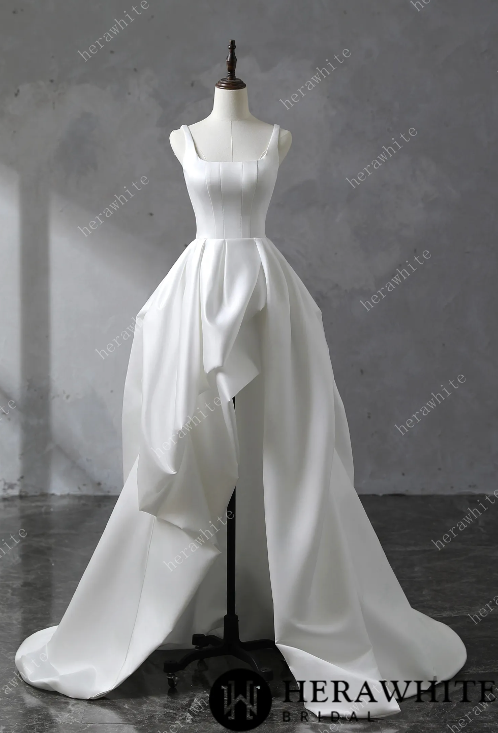 White satin wedding dress on a mannequin against a gray background