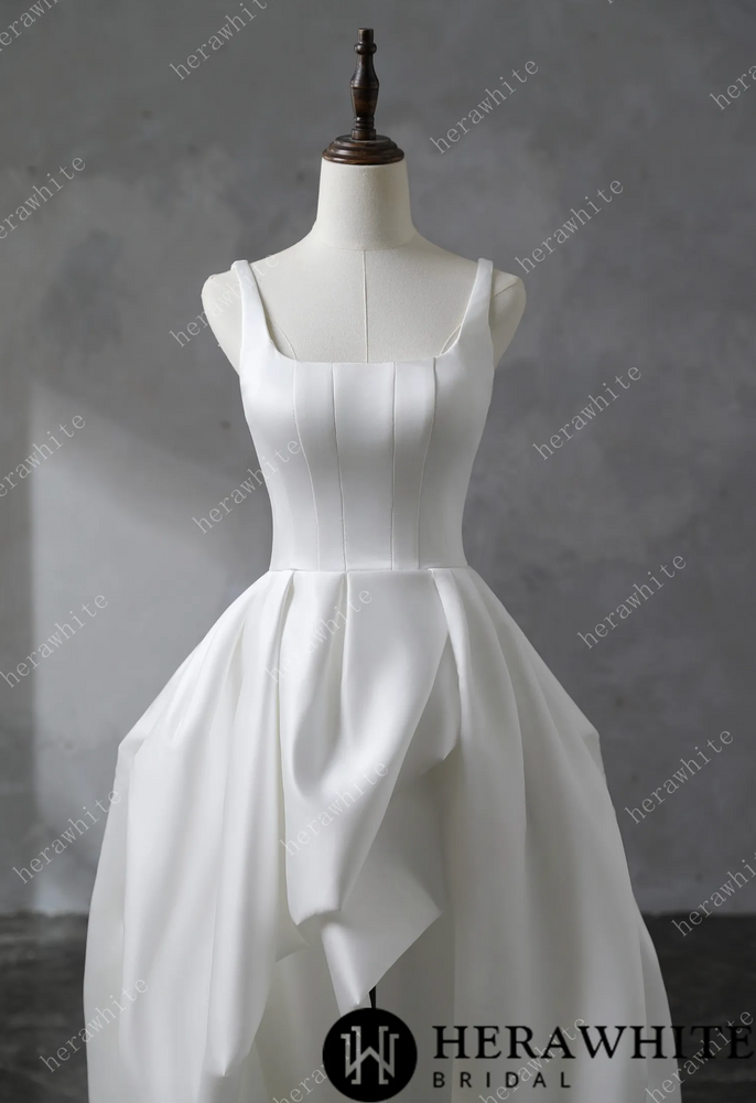 
                      
                        White satin wedding dress on a mannequin against a gray background
                      
                    