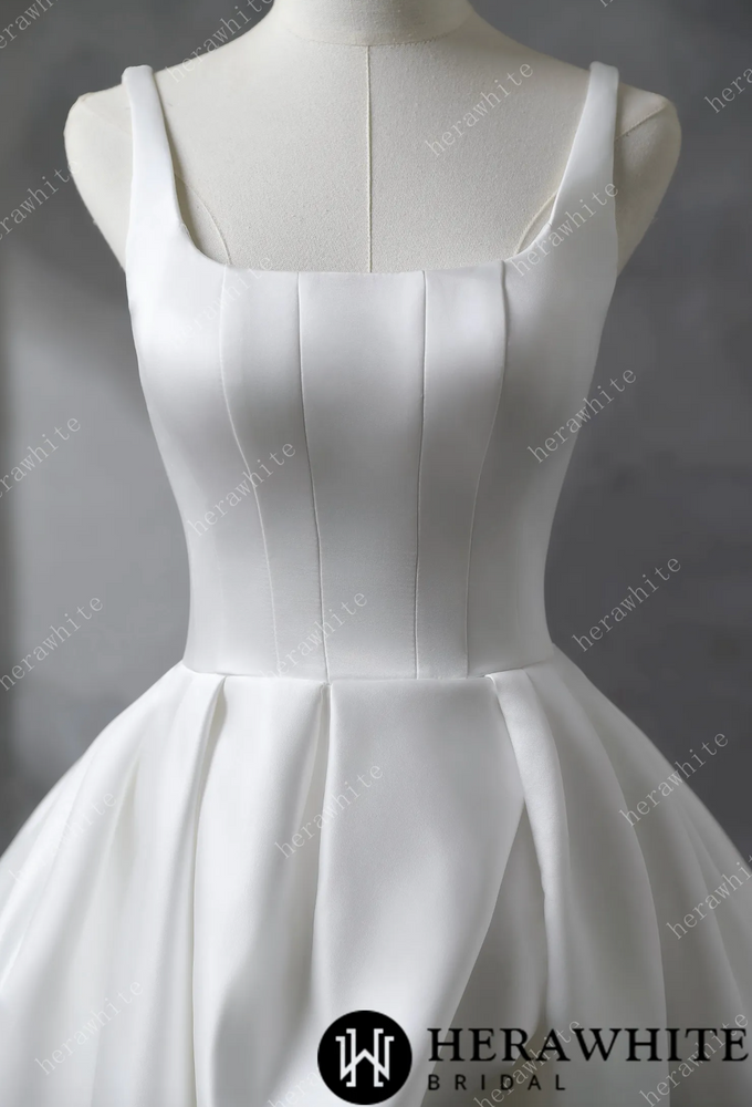 
                      
                        White satin wedding dress on a mannequin against a gray background
                      
                    