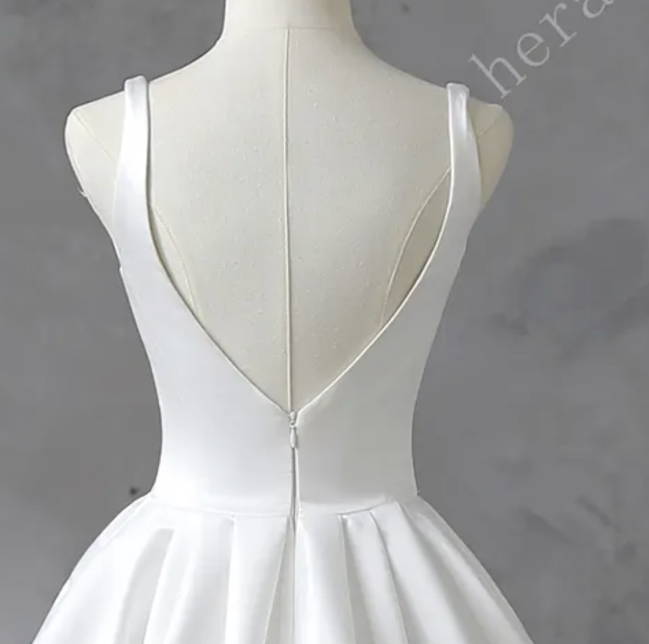 
                      
                        White satin wedding dress on a mannequin against a gray background
                      
                    