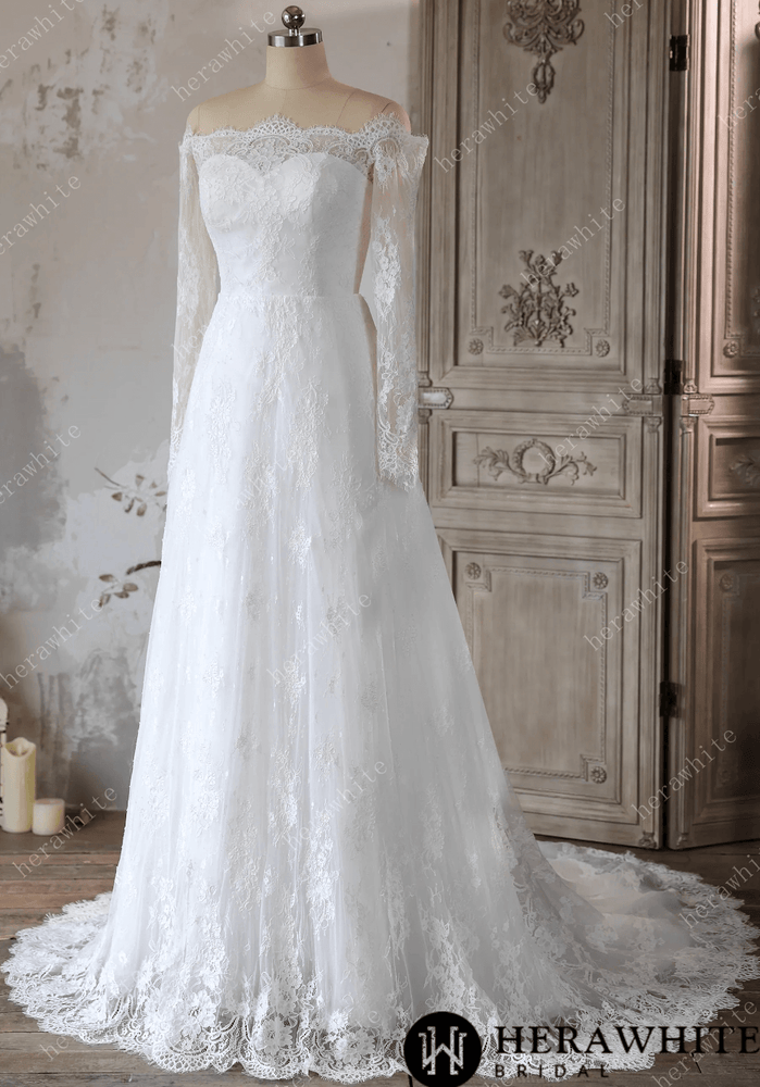 
                      
                        White lace wedding dress on a mannequin against a decorative wall.
                      
                    