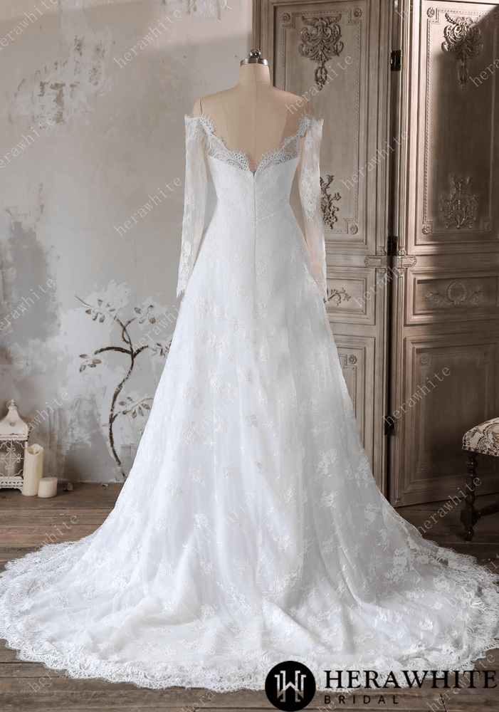 
                      
                        White lace wedding dress on a mannequin against a decorative wall.
                      
                    