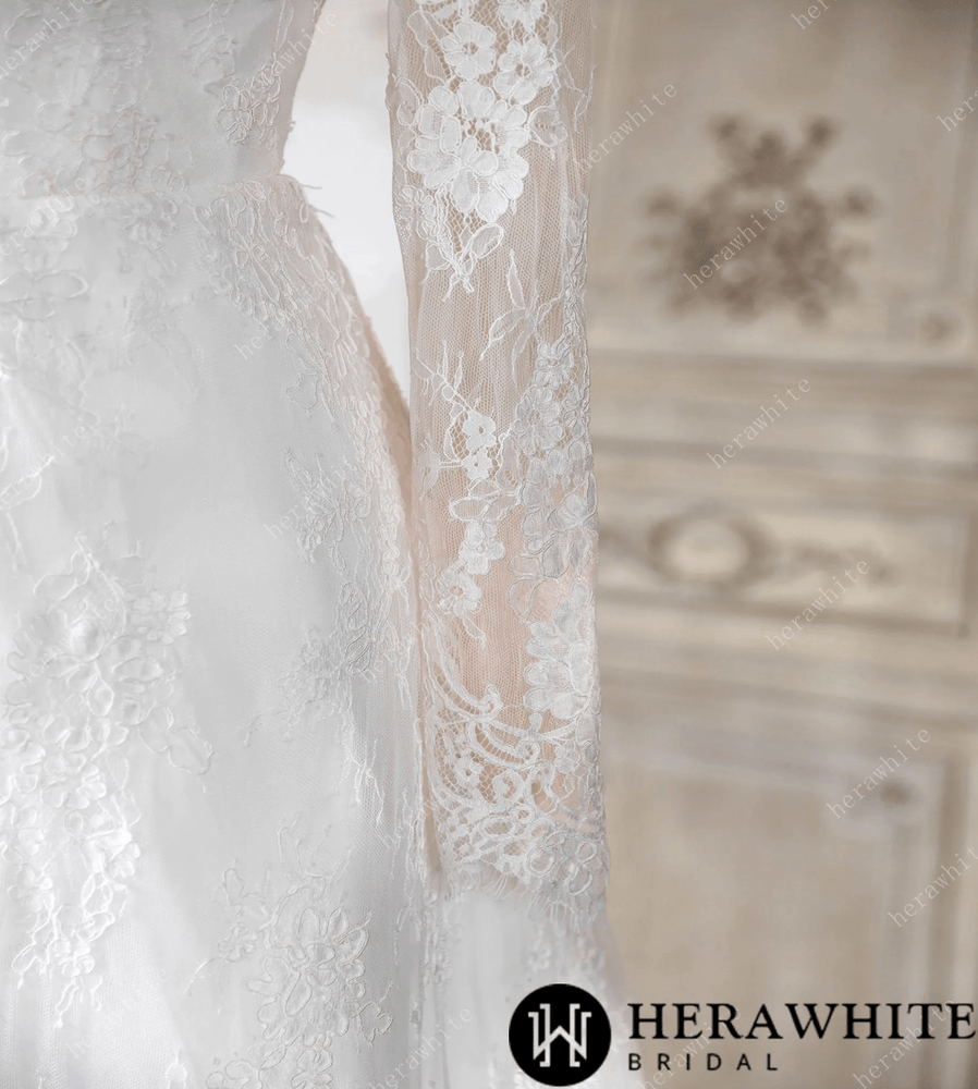 
                      
                        White lace wedding dress on a mannequin against a decorative wall.
                      
                    