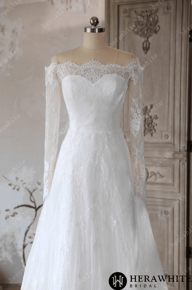 
                      
                        White lace wedding dress on a mannequin against a decorative wall.
                      
                    