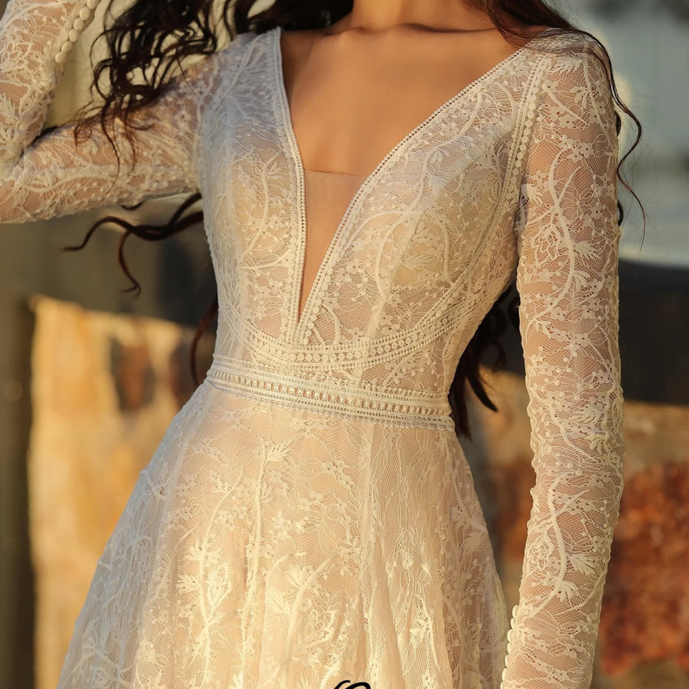 
                      
                        Boho A-Line V Neckline Long Sleeve Wedding Dress in delicate lace with button detail and lace trim accents.
                      
                    