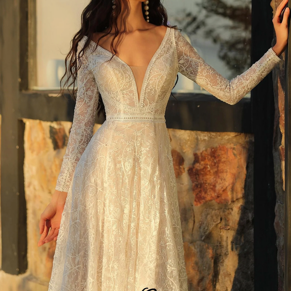 
                      
                        Boho A-Line long sleeve wedding dress with deep V-neckline and lace detailing, capturing vintage elegance.
                      
                    