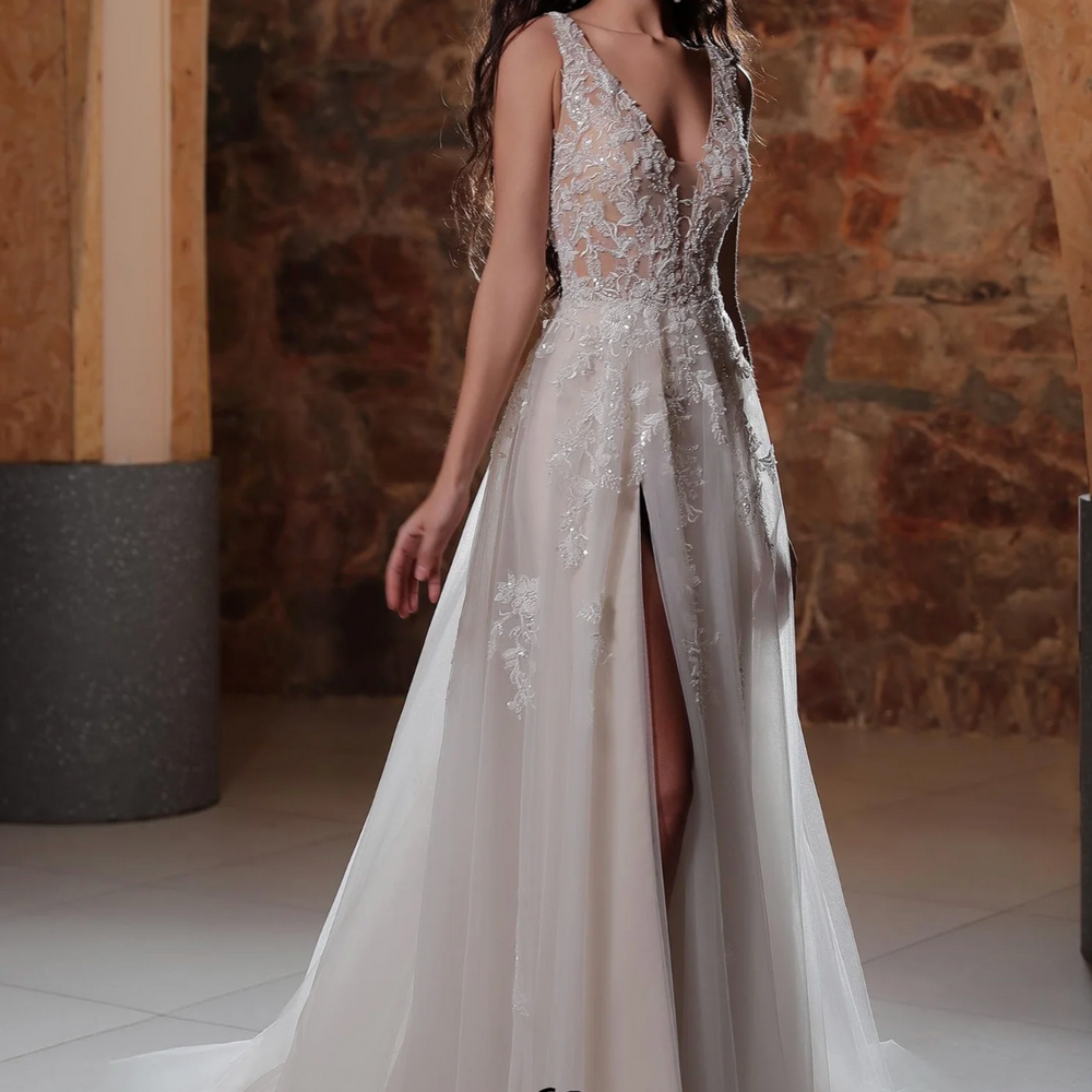 
                      
                        Elegant plunging V-neck A-line wedding dress with lace appliqués and thigh-high slit, showcasing refined bridal style.
                      
                    