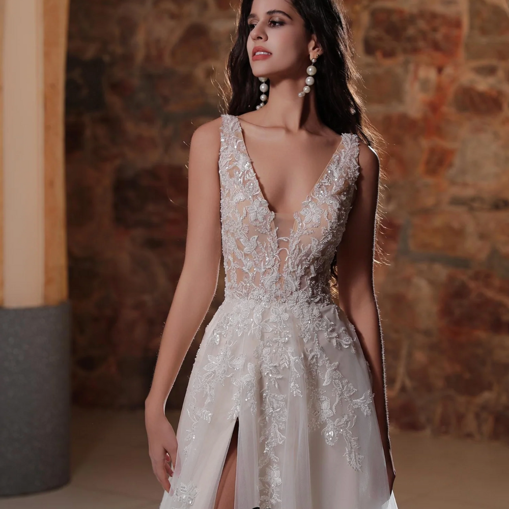 
                      
                        Plunging V-neckline A-line wedding dress with lace details and thigh-high slit, showcasing elegant bridal style.
                      
                    