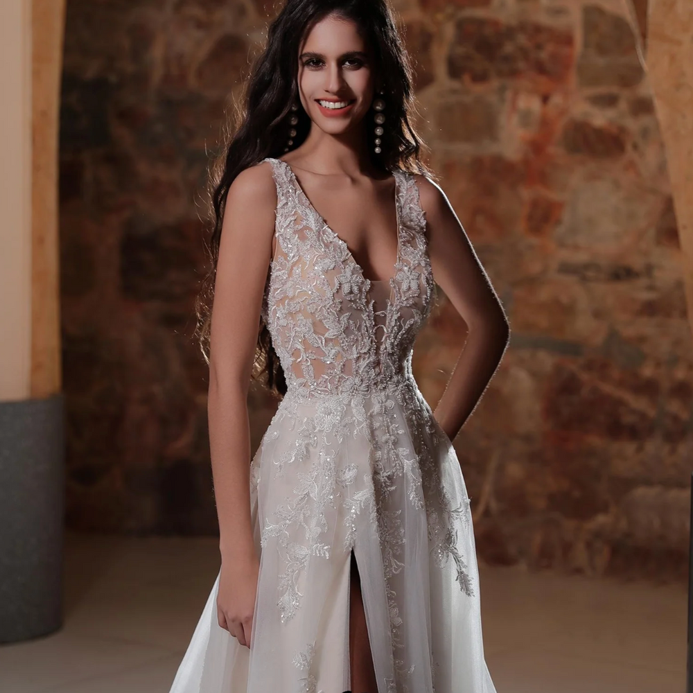 
                      
                        Elegant bride in a plunging V-neckline A-line wedding dress with lace appliqués and thigh-high slit.
                      
                    