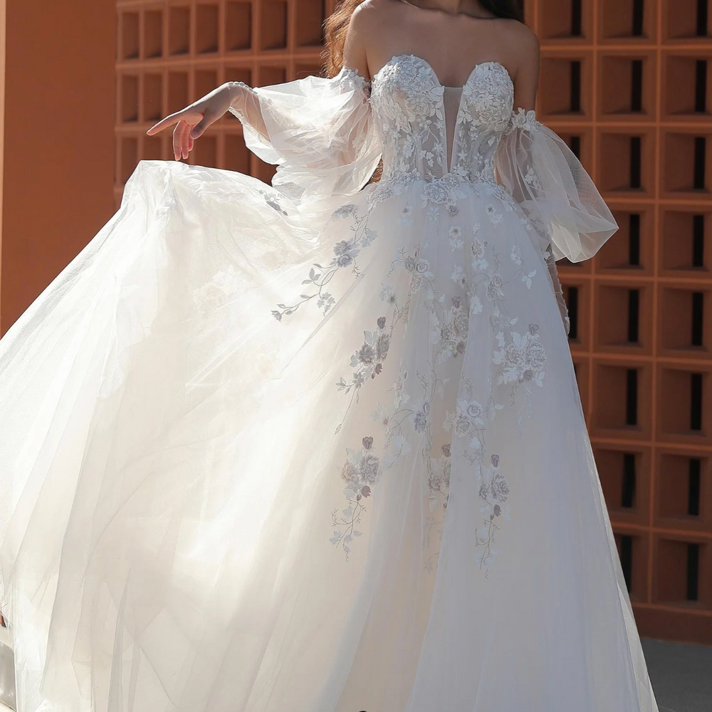 
                      
                        Stunning wedding gown with puffed sleeves and delicate embroidery, showcasing a romantic design and sweetheart neckline.
                      
                    