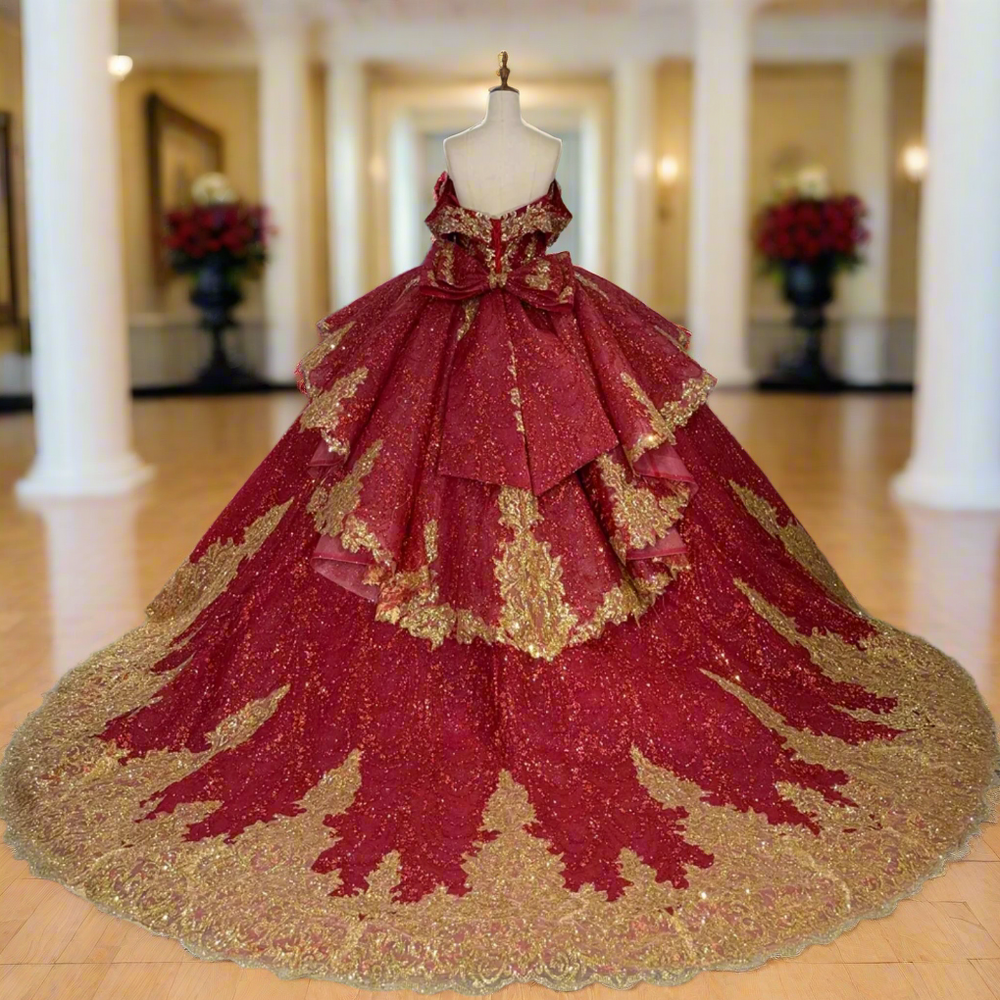 Red and gold ball gown on a mannequin in a room with other dresses.