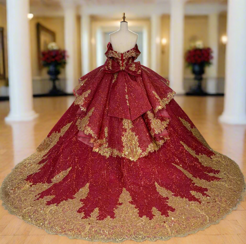 Red and gold ball gown on a mannequin in a room with other dresses.