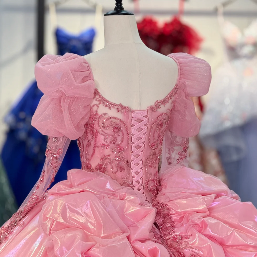 
                      
                        Pink ball gown on a mannequin with intricate details in a blurred store setting
                      
                    