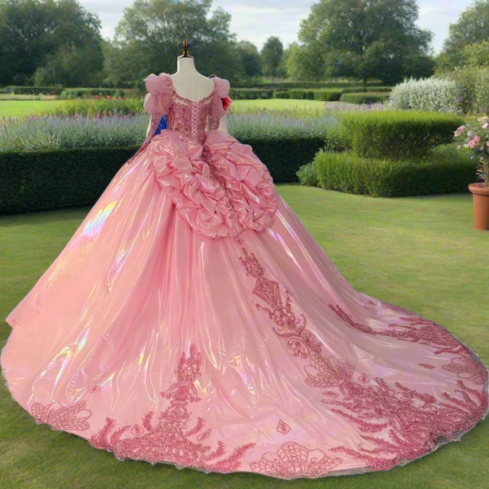 
                      
                        Pink ball gown with intricate details on a mannequin in a room with other dresses.
                      
                    