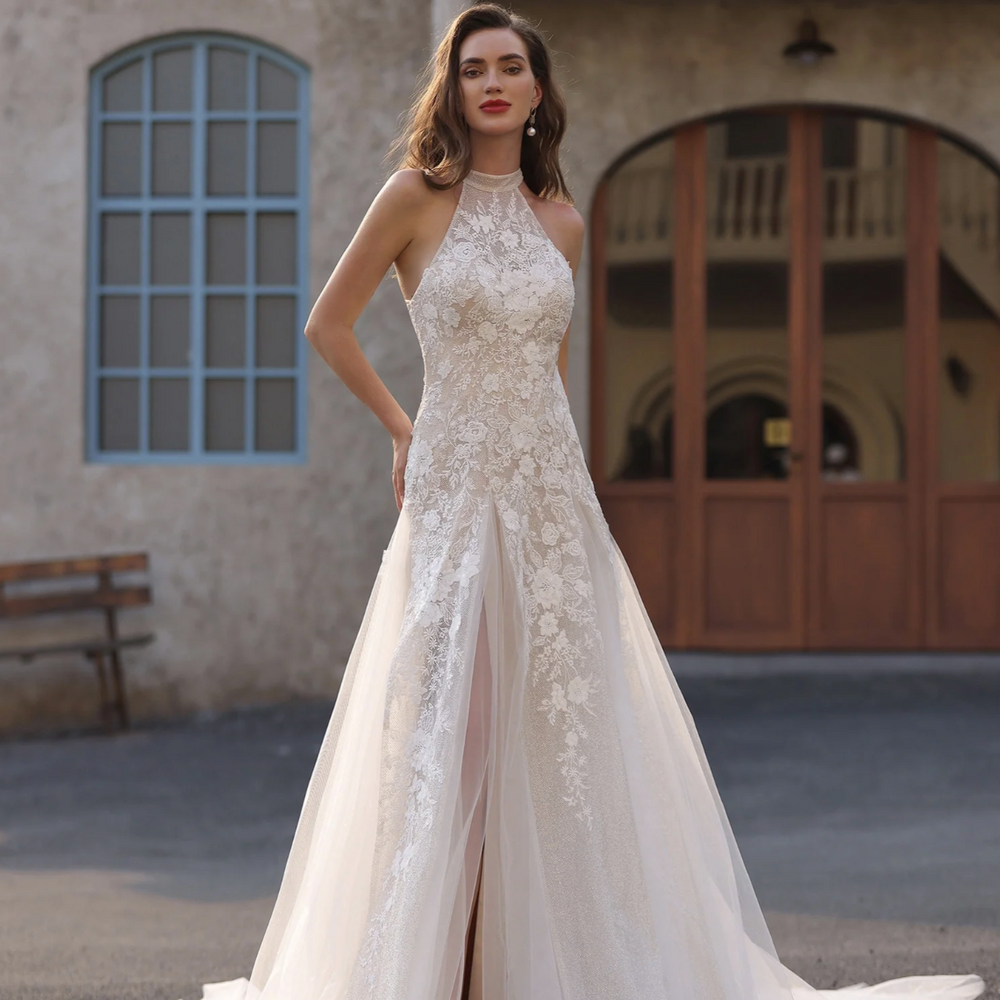 Woman in a white lace wedding dress standing in front of a building with decorative elements.