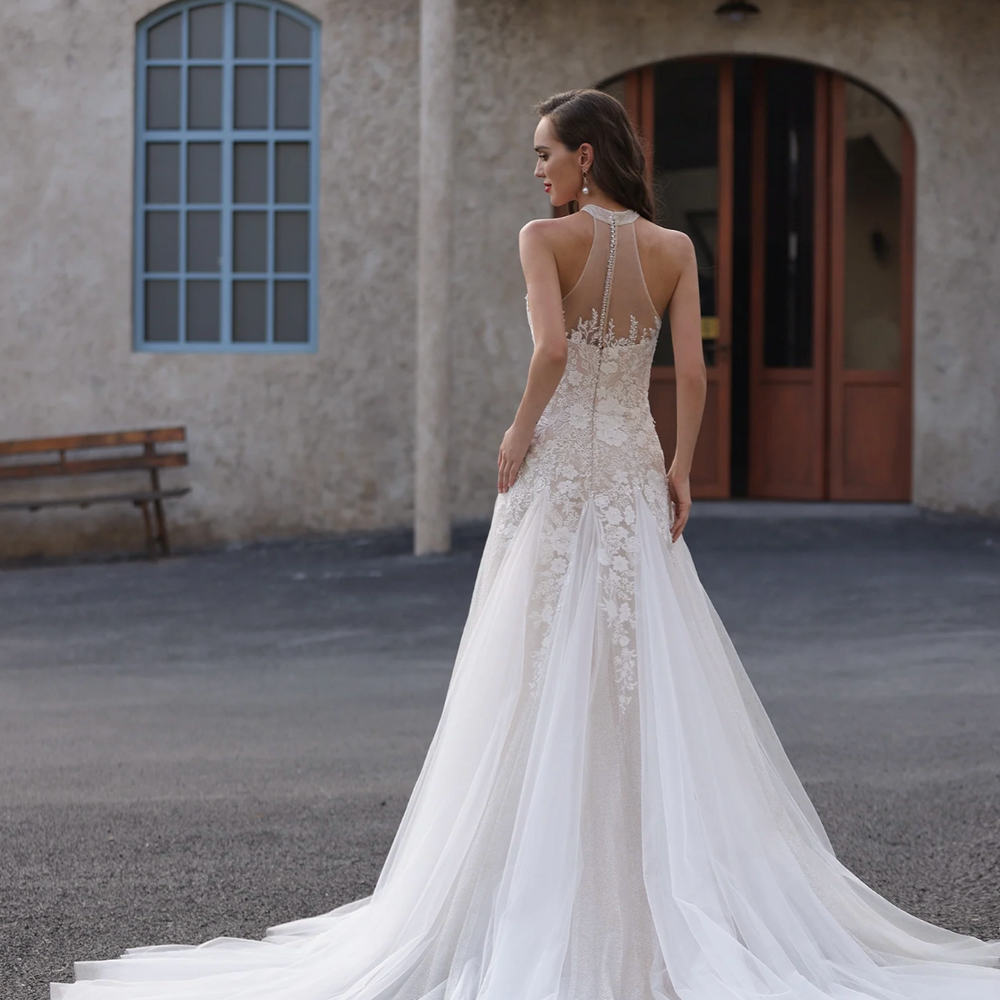 
                      
                        Woman in a white wedding dress standing in front of a building with architectural details.
                      
                    