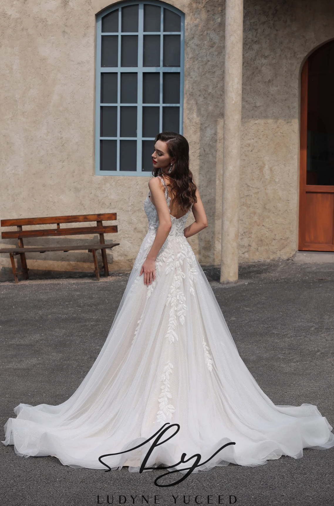 Woman in a white wedding dress standing outdoors with a building in the background