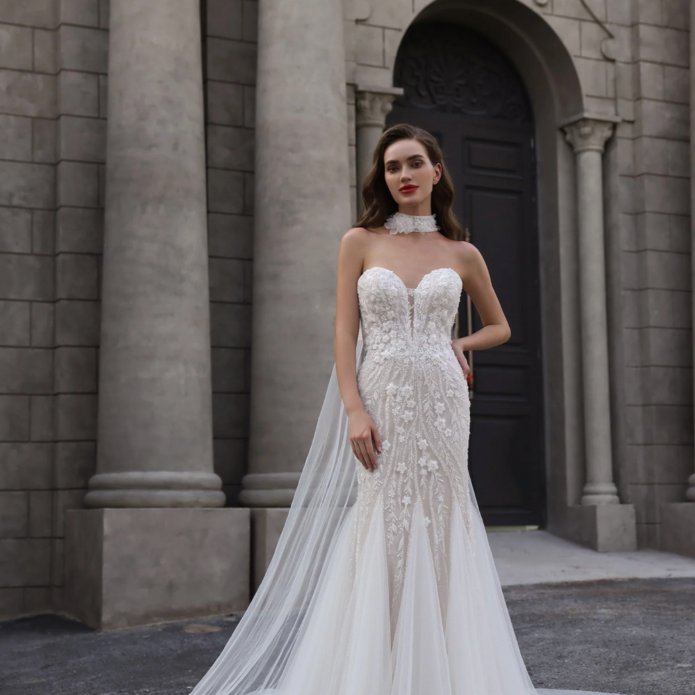 Woman in a white wedding dress standing in front of a stone building